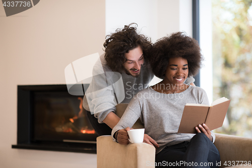 Image of multiethnic couple hugging in front of fireplace