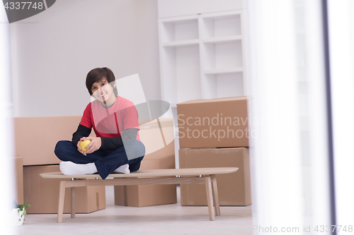 Image of boy sitting on the table with cardboard boxes around him