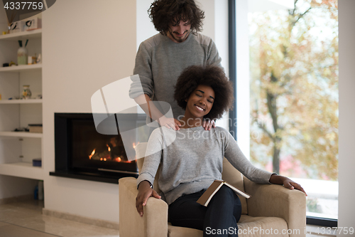 Image of multiethnic couple hugging in front of fireplace