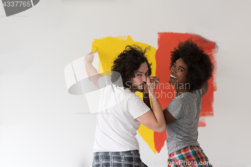 Image of multiethnic couple painting interior wall