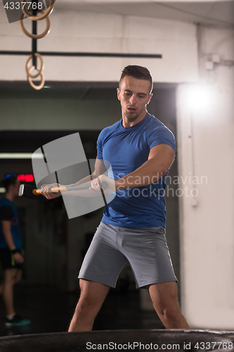 Image of man workout with hammer and tractor tire