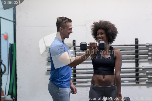 Image of black woman doing bicep curls with fitness trainer