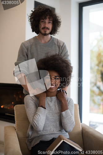 Image of multiethnic couple hugging in front of fireplace