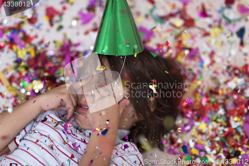 Image of kid blowing confetti while lying on the floor