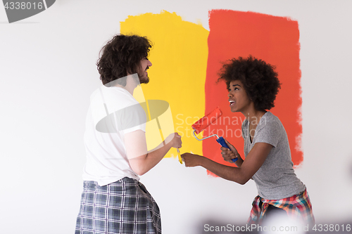 Image of multiethnic couple painting interior wall