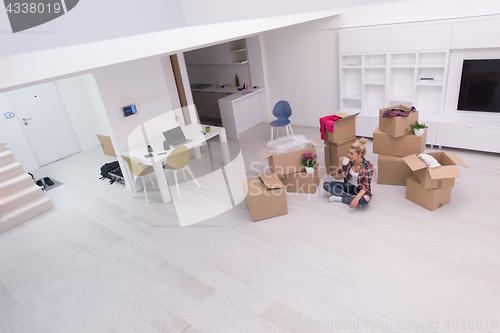 Image of woman with many cardboard boxes sitting on floor