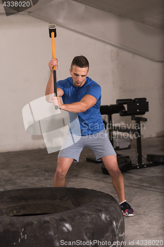 Image of man workout with hammer and tractor tire