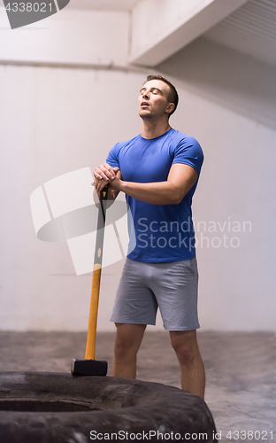 Image of man workout with hammer and tractor tire