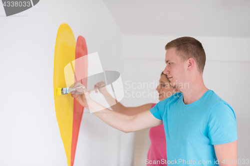 Image of couple are painting a heart on the wall