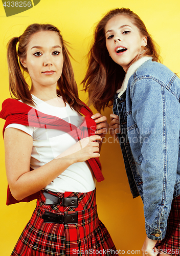 Image of lifestyle people concept: two pretty young school teenage girls having fun happy smiling on yellow background