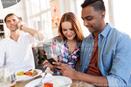 Image of happy friends with smartphone at restaurant