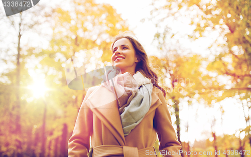 Image of beautiful happy young woman walking in autumn park