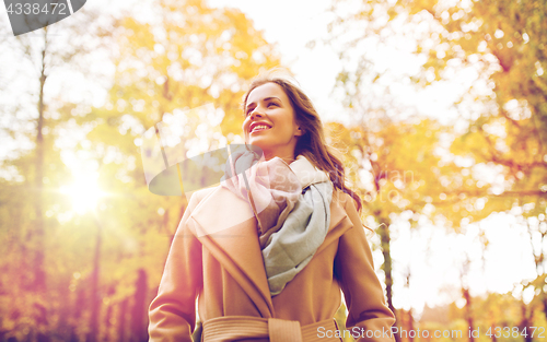 Image of beautiful happy young woman walking in autumn park