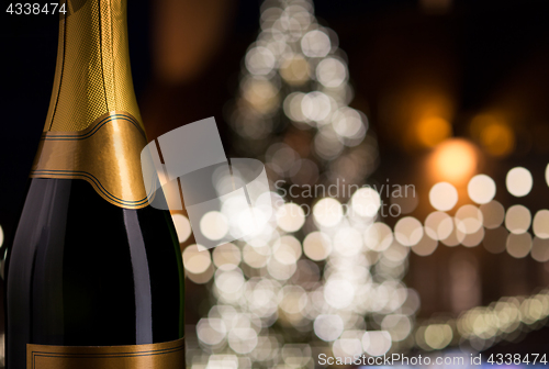 Image of close up of champagne bottle over christmas lights