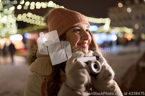 Image of happy young woman with camera at christmas market