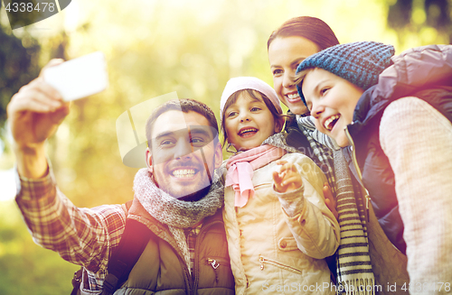 Image of family taking selfie with smartphone outdoors