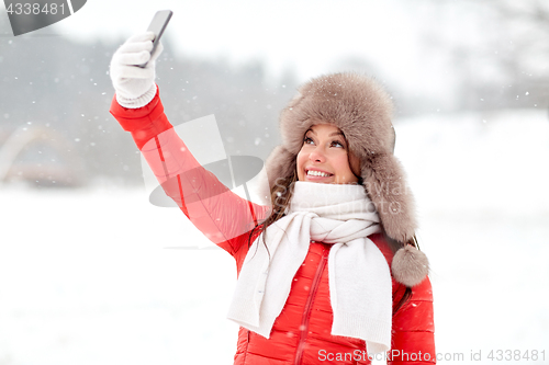 Image of happy woman taking selfie outdoors in winter