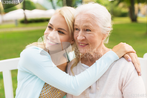 Image of daughter with senior mother hugging on park bench