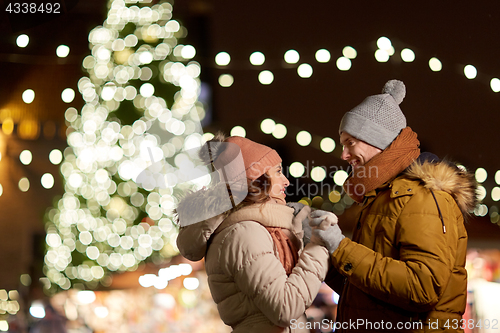 Image of happy couple holding hands at christmas tree