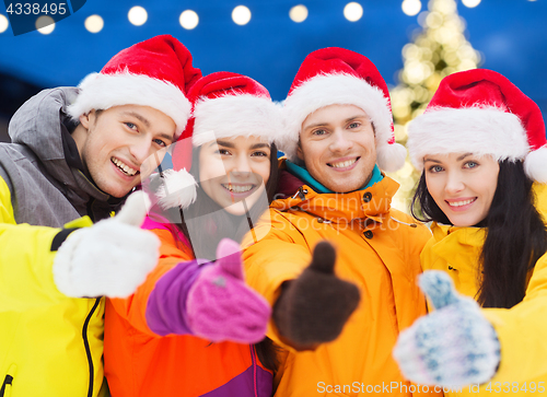 Image of happy friends in santa hats and ski suits outdoors