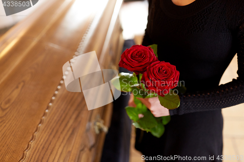 Image of woman with red roses and coffin at funeral