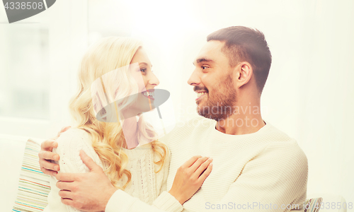 Image of happy couple hugging on sofa at home
