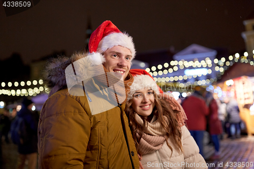 Image of happy couple in santa hats at christmas market