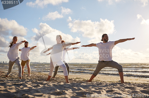 Image of group of people making yoga exercises on beach