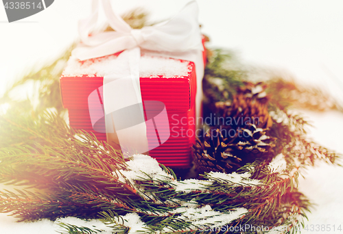 Image of christmas gift and fir wreath with cones on snow