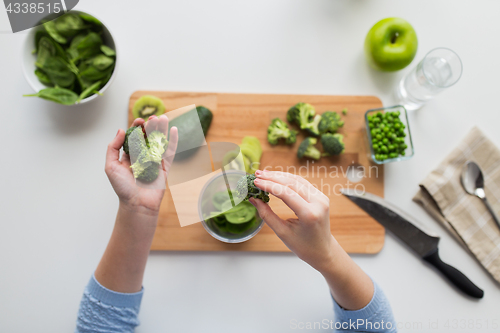 Image of woman hand adding broccoli to measuring cup