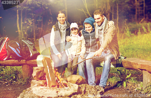 Image of happy family sitting on bench at camp fire