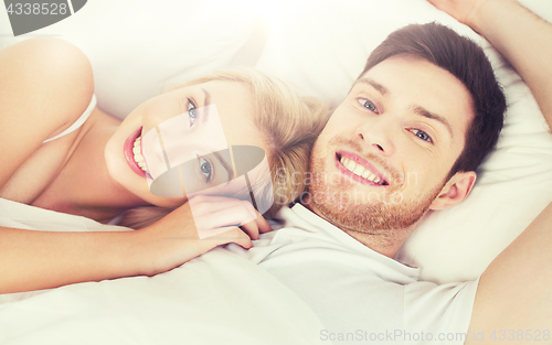 Image of happy couple lying in bed at home