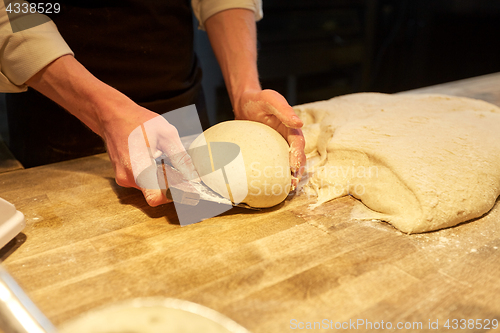 Image of baker portioning dough with bench cutter at bakery