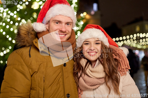 Image of happy couple in santa hats at christmas tree