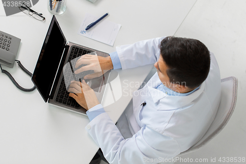 Image of man doctor typing on laptop at clinic