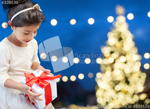 Image of happy girl with gift box over christmas lights