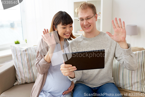Image of husband and pregnant wife with tablet pc at home