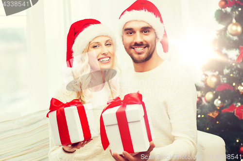 Image of happy couple at home with christmas gift boxes