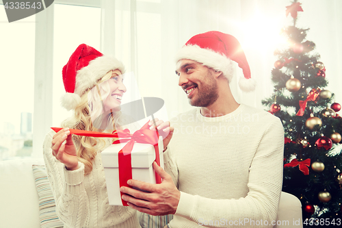 Image of happy couple at home with christmas gift box