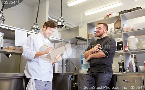 Image of happy smiling chef and cook at restaurant kitchen