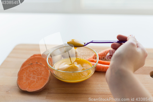 Image of hand with vegetable puree or baby food in spoon