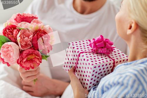 Image of close up of couple with gift and flowers in bed