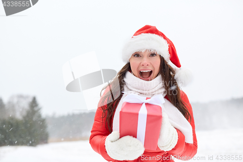 Image of happy woman in santa hat with chrismas gift