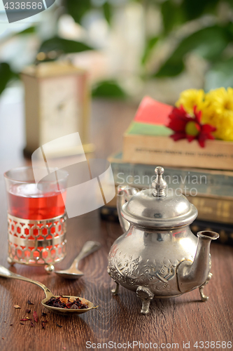 Image of Dry tea leaves on spoon and teapot