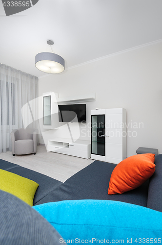 Image of White living room with TV set, chair and grey sofa