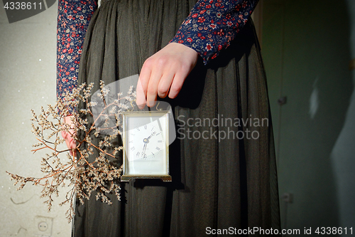 Image of Girl with vintage dress holding clock