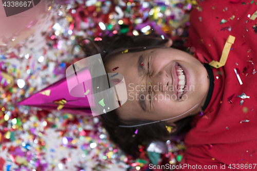 Image of kid blowing confetti while lying on the floor