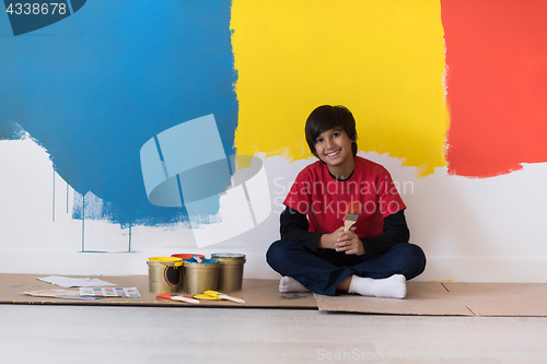 Image of young boy painter resting after painting the wall