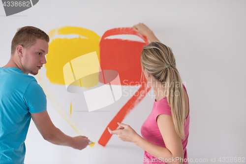 Image of couple are painting a heart on the wall