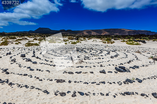 Image of A round stone pattern in the sand by a beach on Lanzarote.